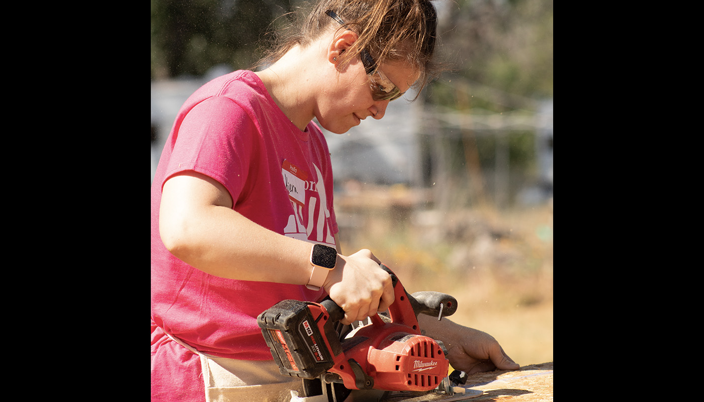 Woman volunteer cutting a board.